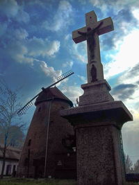 Low angle view of cross by building against sky