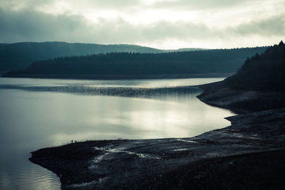 Scenic view of lake by silhouette mountain against sky