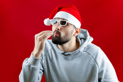 Portrait of man wearing sunglasses against red background