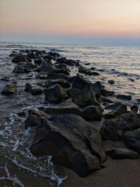 Scenic view of rocks at beach during sunset