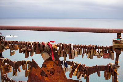 Close-up of padlocks hanging on railing against sky