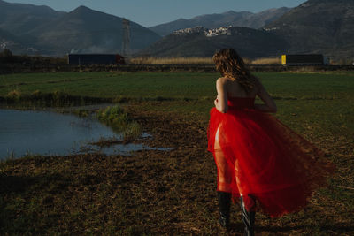 Rear view of young woman wearing red dress while walking on land