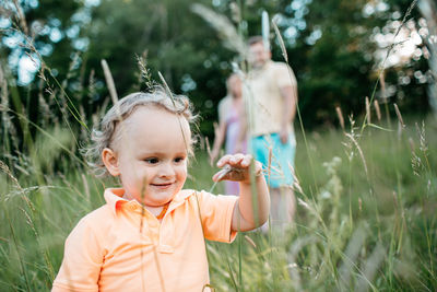 Close-up of cute boy on field with parents in background