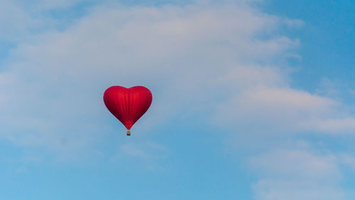 Red heart shaped hot air balloon against sky