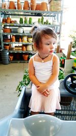 Cute girl standing in toy car at retail shop