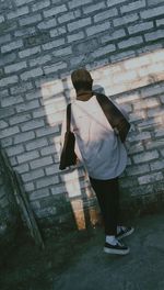 Low section of woman standing against brick wall