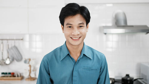 Handsome gay, attractive young gay smile to camera in kitchen room.