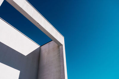 Low angle view of wall with shadow against clear sky on sunny day