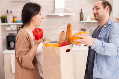 Man and woman holding fruits at home