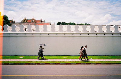 People walking on road against sky