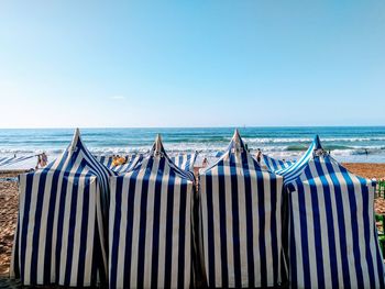 Deck chairs on beach against clear blue sky