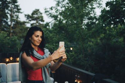 Smiling mid adult woman taking selfie in balcony during sunset