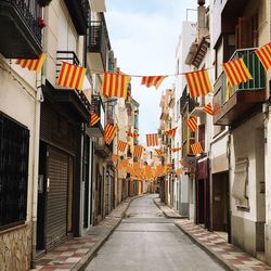 Flags hanging amidst buildings in city against sky