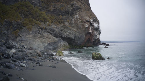 Rock formation on beach against sky