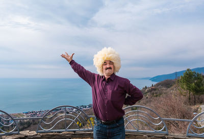 Asian man  in  white sheepskin hat dancing lezginka on backdrop of black sea and city gagra abkhazia