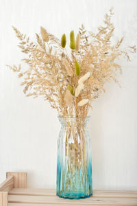 Fall winter home decor blue glass vase with dry grass on wooden shelf.  boho trendy interior decor.