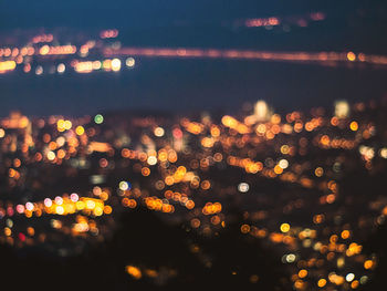 Defocused image of illuminated city against sky at night