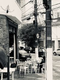 Empty chairs and tables in city against buildings