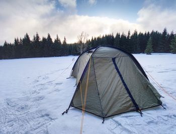 Tent on snow covered field against sky