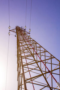 Low angle view of electricity pylon against clear blue sky