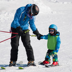 Father and son skiing on snow covered field during winter