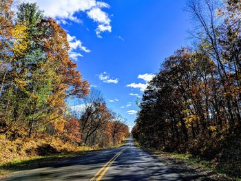 Road amidst trees against sky during autumn