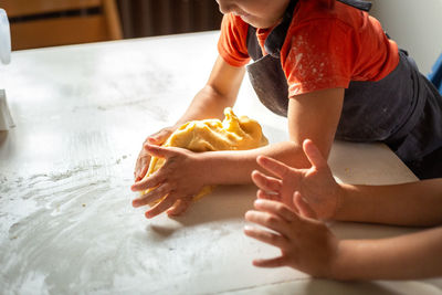 Hands of two little girls preparing dough