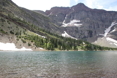 Scenic view of rocky mountains by lake during winter