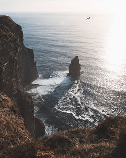 Scenic view of sea by rock formation against sky