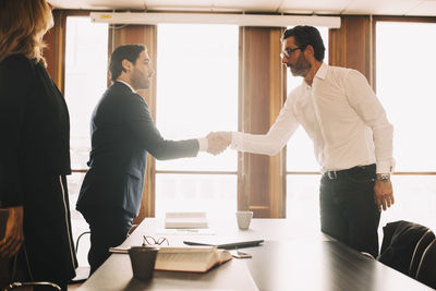 Businessman shaking hands with male lawyer after meeting in board room