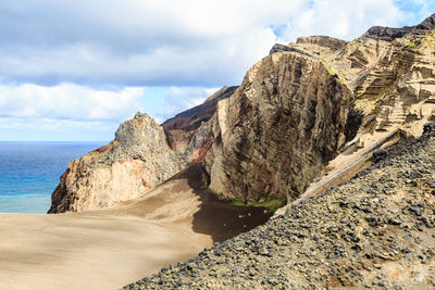 Rock formations on beach against sky