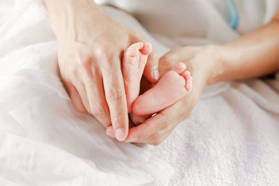 Close-up of woman holding hands on bed