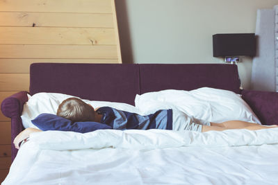 Boy sleeping on bed at home