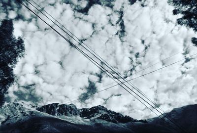 Low angle view of power lines against cloudy sky