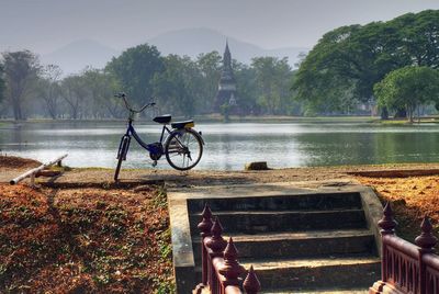 Bicycle by lake against trees
