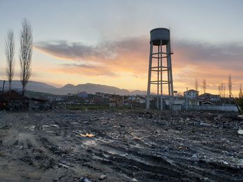 Factory on field against sky during sunset