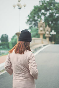 Rear view of woman standing on road