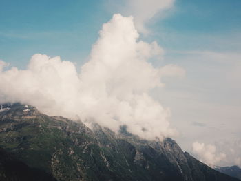 Scenic view of clouds covering mountain against blue sky