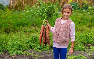 Portrait of smiling young woman standing against plants