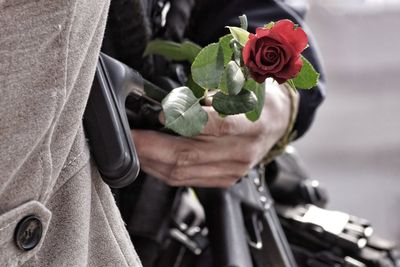 Midsection of person holding rose outdoors