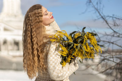 A woman with a bouquet of acacia flowers. the concept of the spring - march 8, easter, women's day.