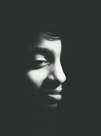 Close-up of young woman against black background