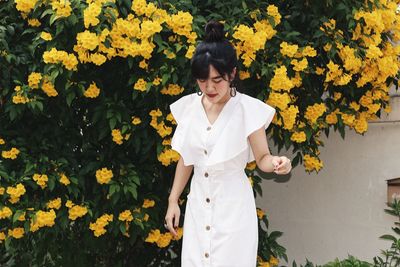 Young woman standing by yellow flowering plants