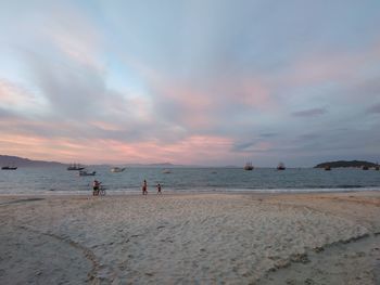 People on beach against sky during sunset