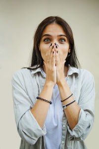 Portrait of young woman looking away while standing against white background