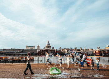 People with bubbles on street against sky in city