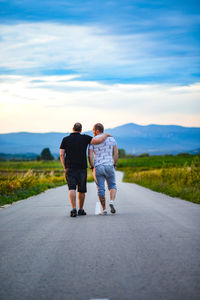 Rear view of friends walking on road