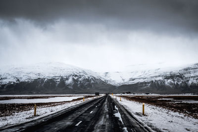 Road leading towards snow covered mountain against sky