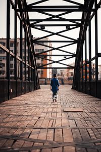 Rear view of man walking on cobblestone