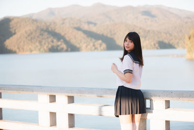 Portrait of woman standing on bridge over river